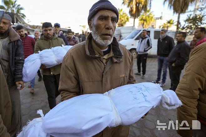 [데이르 알-발라(가자지구)=AP/뉴시스]이스라엘군의 공습으로 2일 밤 생후 6개월 된 조카를 잃은 팔레스타인의 한 남성이 3일 가자지구 데이르 알-발라의 알 아크사 순교자병원에서 조카의 시신을 안고 장례 기도를 준비하고 있다. 가자지구에서 2일 밤부터 3일 새벽 사이 어린이를 포함해 최소 30명이 이스라엘군의 공습으로 추가로 사망, 24시간 동안 사망자 수가 56명으로 늘어났다고 병원 직원들이 3일 밝혔다. 아일랜드가 7일 이스라엘에 대한 집단학살 혐의 국제형사재판소(ICC) 제소에 공식 참여했다.  2025.01.08.