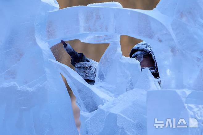 [하얼빈=AP/뉴시스] 8일 중국 헤이룽장성 하얼빈에서 열린 제41회 하얼빈 빙설제에서 한 얼음 조각가가 작업을 하고 있다. 2025.01.10.