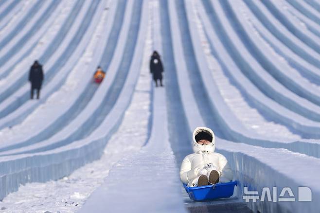 [하얼빈=AP/뉴시스] 6일 중국 헤이룽장성 하얼빈에서 열린 제41회 하얼빈 빙설제에서 관광객들이 얼음 미끄럼틀을 타고 있다. 2025.01.10.