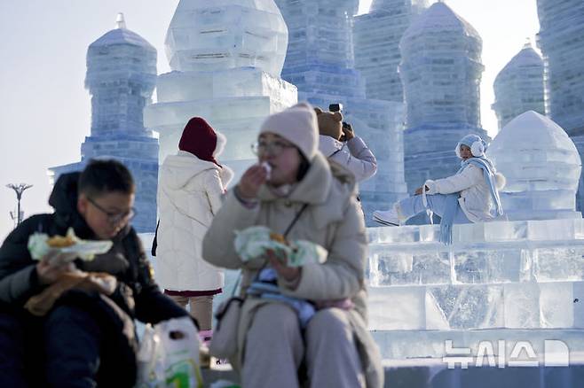 [하얼빈=AP/뉴시스] 6일 중국 헤이룽장성 하얼빈에서 열린 제41회 하얼빈 빙설제에서 관광객들이 기념촬영을 하고 있다. 2025.01.10.