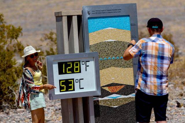 미국 캘리포니아주 평균 기온이 섭씨 53도까지 치솟았던 지난해 7월 데스밸리 국립공원에서 관광객들이 온도계를 배경으로 사진을 찍고 있다. 데스밸리=AP 연합뉴스 자료사진