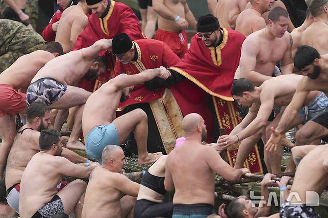 [베오그라드=AP/뉴시스] 19일(현지 시간) 세르비아 베오그라드에서 주현절 기념행사가 열려 붉은 옷을 입은 정교회 사제들이 십자가를 찾기 위해 다뉴브강에 뛰어들었던 신자들이 물 밖으로 나오는 것을 돕고 있다. 이날 동방 정교회 사제가 물에 던진 나무 십자가를 찾아오는 사람뿐 아니라 이를 찾기 위해 물에 뛰어든 사람 모두가 일 년 내내 건강하게 지낼 수 있다고 믿는다. 2025.01.20.