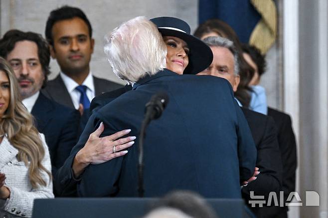 [워싱턴=AP/뉴시스] 도널드 트럼프 미국 대통령 당선인이 20일(현지 시간) 본인의 제47대 대통령 취임식이 열리는 미 연방의회 의사당 로툰다 홀에 입장해 앞서 입장한 부인 멜라니아 여사에게 입 맞추고 있다. 2025.01.21.