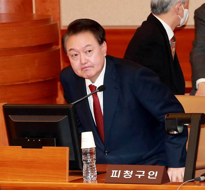 탄핵심판 3차 변론기일에 출석한 윤석열 대통령이 21일 오후 서울 종로구 재동 헌법재판소 심판 법정의 피청구인 자리에 앉고 있다.  사진공동취재단