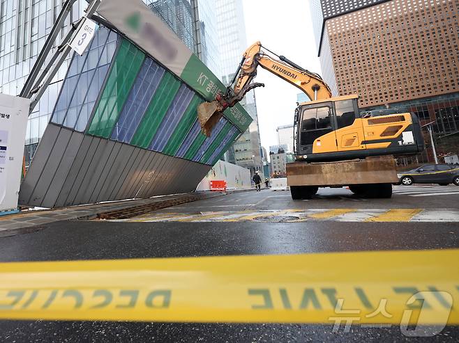 눈이 내리고 바람이 강하게 분 27일 오후 서울 종로구 KT 광화문 사옥 리모델링 현장에서 굴삭기가 강풍에 쓰러져 기울어진 공사장 가림막을 받치고 있다. 2025.1.27/뉴스1 ⓒ News1 황기선 기자