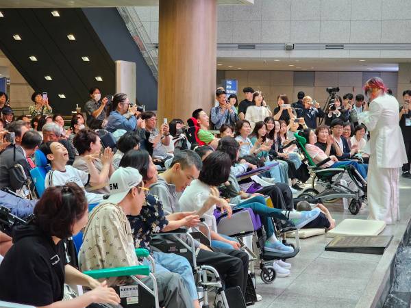 김장훈이 지난해 4월 강남구 코엑스에서 열린 ‘누워서 보는 콘서트’에서 맨 앞줄에 앉은 중증장애인 관객에게 다가가 이야기를 건네고 있다. 김장훈 제공