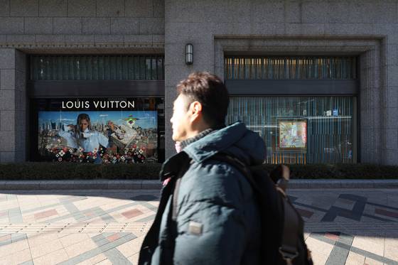 A pedestrian walks by a row of luxury good stores at a department store in Seoul on Jan. 2. [YONHAP]