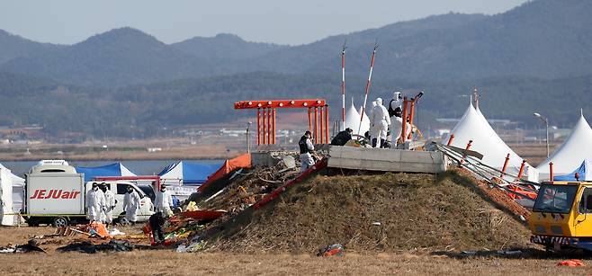 2일 전남 무안국제공항 제주항공 여객기 참사 현장에서 항공·철도사고 조사위원회(ARAIB) 관계자들이 로컬라이저(방위각 표시 시설)가 설치된 콘크리트 둔덕을 조사하고 있다.  [뉴시스]
