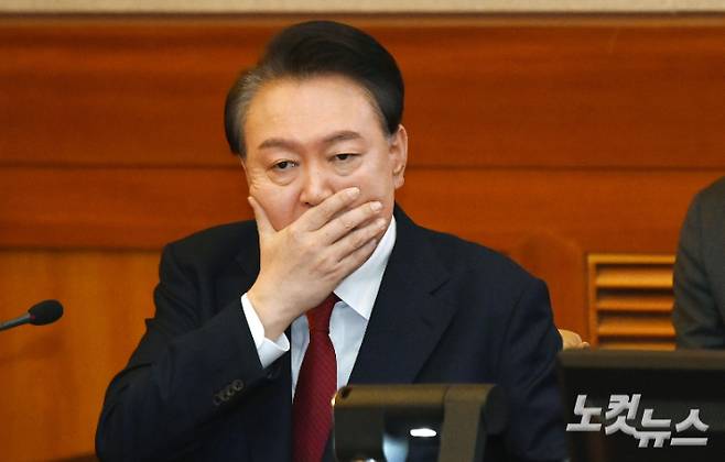 윤석열 대통령이 6일 오전 서울 종로구 헌법재판소 대심판정에서 열린 탄핵심판 6차 변론기일에 출석, 입을 가린 채 변호인에게 말을 하고 있다. 사진공동취재단