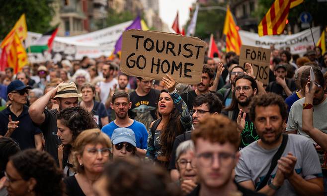 스페인 바르셀로나 주민들이 지난 2024년 6월19일(현지시간) 시내 중심가에서&nbsp;‘관광객들은 집으로 돌아가라’는 문구가 적힌 손팻말을 들고 과잉관광에 항의하는 구호를 외치고 있다. 바르셀로나=AP연합뉴스