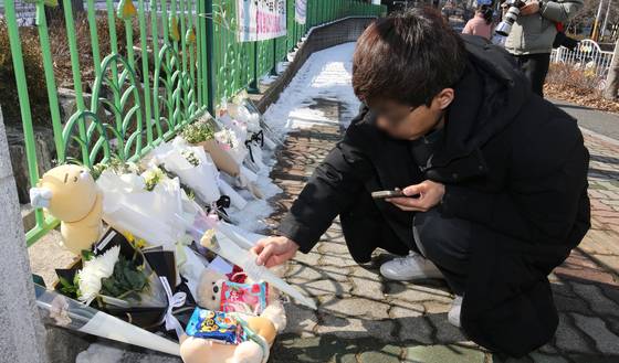 A student mourns the death of 7-year-old Kim Ha-neul while placing flowers at an elementary school in Seo District, Daejeon, on Feb. 11. [NEWS1]