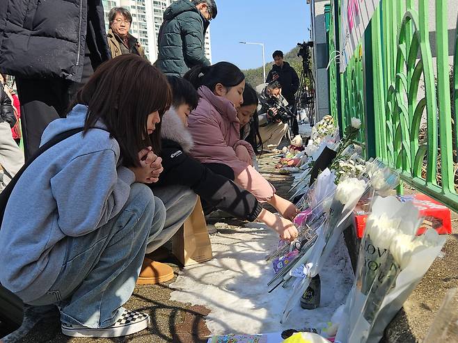 숨진 김하늘(8)양과 같은 학교를 다니는 학생들이 11일 김양을 추모하며 학교 담벼락에 하얀 꽃을 가져다 놓고 있다. / 안태민 기자