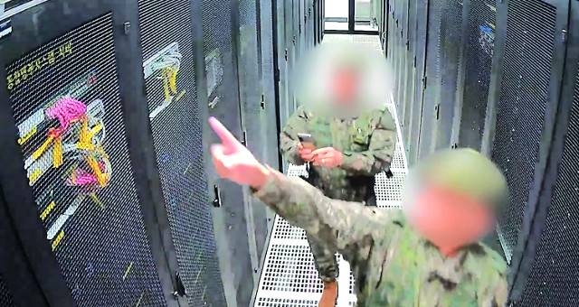 지난해 12월 3일 비상계엄 선포 당시 경기도 과천 중앙선거관리위원회 청사에 투입된 계엄군이 선거 시스템 서버를 손으로 가리키고 있다. 뒤에 있는 계엄군이 서버를 스마트폰으로 촬영하고 있다. 이 장면은 선관위 CCTV에 포착된 것이다. 국회 행정안전위원회 제공