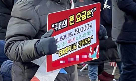 지난 8일 서울 종로구 동화면세점 앞에서 ‘대한민국바로세우기운동본부’(대국본) 주최로 열린 윤석열 대통령 탄핵 반대 집회에서 한 참가자가 모바일 판촉 관련 손팻말을 들고 있다. 연합뉴스