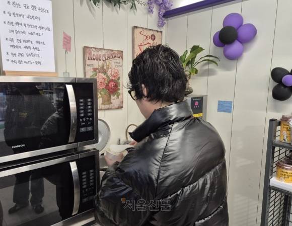 12일 쌀밥과 달걀을 무료로 제공하는 서울의 한 편의점에서 한 손님이 라면과 함께 먹을 밥을 푸고 있다.