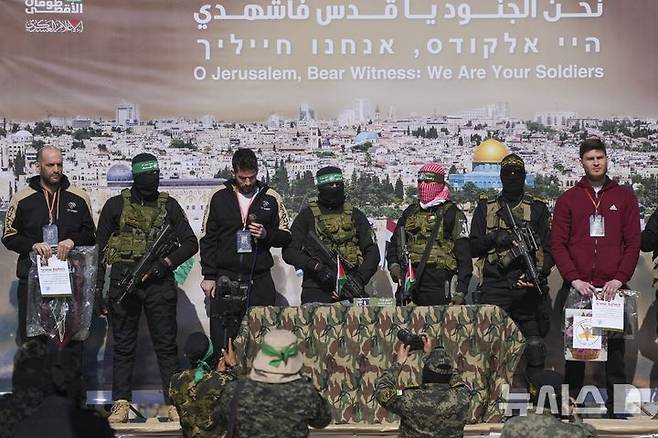 [칸유니스=AP/뉴시스] 휴전 합의의 일환으로 15일(현지 시간) 팔레스타인 무장정파 하마스가 석방한 이스라엘 인질 야이르 호른(46, 맨 왼쪽)과 사기 데켈첸(36, 왼쪽 두 번째), 알렉산드르 트루파노프(29, 맨 오른쪽)가 석방 전 무대에 올라 인사하고 있다. 2025.02.15.