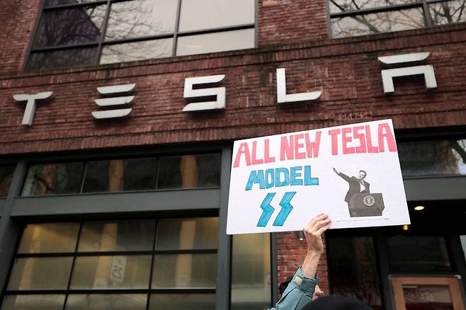 지난 15일(현지시각) 미국 워싱턴 시애틀의 테슬라 매장 앞에서 시위 중인 시민. 로이터 연합뉴스