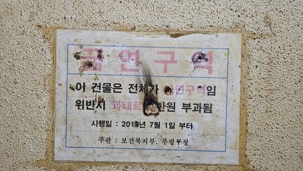 15일 인천 부평구 테마의 거리의 한 건물 비상계단에 부착한 금연구역 경고장이 훼손된 채 관리하지 않고 있다. 장민재기자