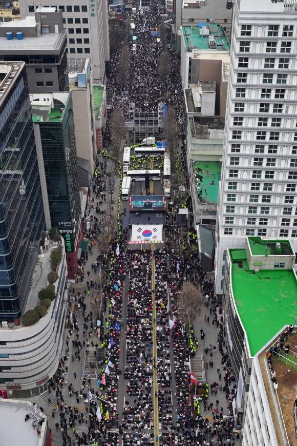 경찰 차벽 사이에 두고… - 지난 15일 오후 5·18 민주화운동 현장인 광주 동구 금남로에서 경찰버스로 만든 차벽을 사이에 두고 윤석열 대통령 탄핵 찬성 집회(아래 쪽)와 반대 집회(위쪽)가 열리고 있다. 민주화의 상징인 동시에 계엄의 트라우마를 안고 사는 도시 광주에서 열린 계엄 옹호 대규모 집회를 두고 여야의 여론전도 가열되고 있다. 이재명 더불어민주당 대표는 “재차 겁탈 살해당하는 모멸감”이라고 했고, 국민의힘은 “광주가 민주당의 소유물인가”라고 반박했다. 광주 연합뉴스