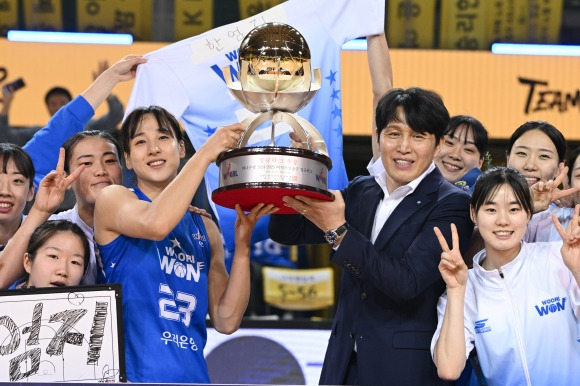 위성우(앞줄 오른쪽 두 번째) 아산 우리은행 감독과 주장 김단비(앞줄 왼쪽 두 번째)가 16일 청주체육관에서 열린 2024~2025 여자프로농구 정규시즌 청주 KB와의 경기에서 정규시즌 우승을 확정한 뒤 우승컵을 함께 들어 올리고 있다. WKBL 제공