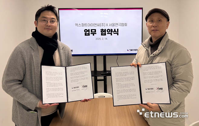 김병준 엑스퍼트아이엔씨 총괄(왼쪽)과 박정의 서울연극협회장이  외국인과 청각장애인 관람객을 위한 AI 자막안경 아울 활성화 업무협약서를 펼쳐보이고 있다.