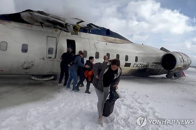 지난 17일(현지시간) 토론토 공항의 전복된 여객기에서 탈출하는 승객들 [토론토 로이터=연합뉴스. 재판매 및 DB 금지]