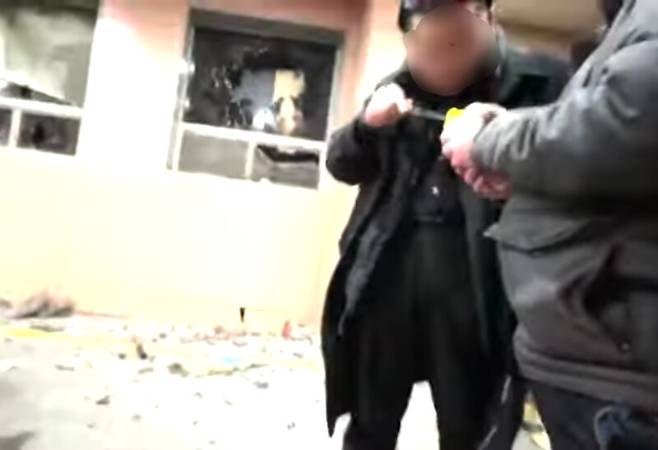 지난달 19일 새벽 서울서부지법 청사 내에서 ㄱ군으로 추정되는 인물이 기름이 담긴 노란 통을 확인하는 모습. 유튜브 채널 ‘제이컴퍼니 정치시사’ 영상 갈무리.