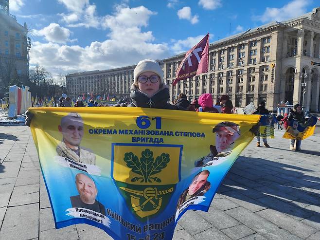 무사 귀환 염원 (키이우=연합뉴스) 신창용 특파원 = 20일(현지시간) 우크라이나 수도 키이우의 독립광장에서 테티아나 씨가 사촌(왼쪽 아래)과 그의 전우들의 사진이 담긴 펼침막을 들고 있다. 2025.02.20 changyong@yna.co.kr