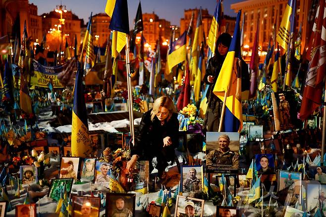 러시아의 우크라이나 침공 3주년을 맞이한 24일(현지시간) 우크라이나 키이우 독립광장에서 한 여성이 전사자를 추모하기 위해 전사자 추모 현장에 촛불을 설치하고 있다. ⓒ 로이터=뉴스1