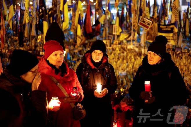 24일(현지시간) 우크라이나 키이우 독립광장에서 열린 러시아의 우크라이나 침공 3주년을 맞아 희생 장병 추모 현장에서 사람들이 촛불을 들며 추모하고 있다. ⓒ 로이터=뉴스1