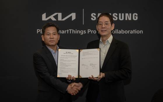 김상대 기아 PBV비즈니스사업부 부사장(왼쪽)과 박찬우 삼성전자 디바이스플랫폼 B2B통합오퍼링 담당 부사장이 스페인 타라고나에서 열린 '기아 EV 데이' 행사에서 업무 협약을 맺은 뒤 손을 맞잡았다. 기아 제공