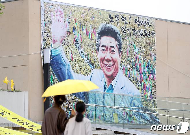 고 노무현 전 대통령 서거 14주기 추도식을 하루 앞둔 22일 오후 경남 김해 봉하마을에서 노란 우산을 쓴 시민들이 깨어있는 시민문화체험전시관 앞을 지나가고 있다. 2023.5.22/뉴스1 ⓒ News1 윤일지 기자