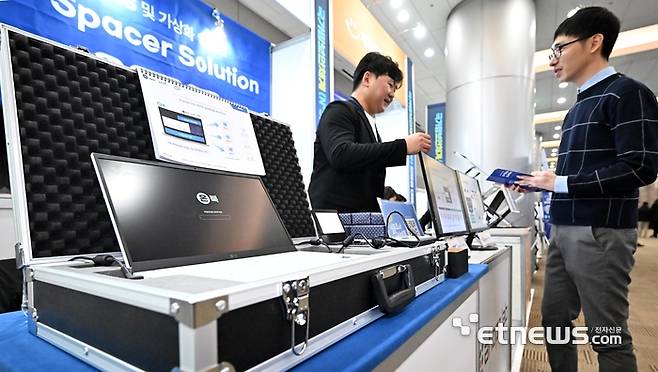 국가망보안체계(N²SF) 전망과 대응 콘퍼런스가 28일 서울 강남구 코엑스에서 열렸다. 참석자가 아홉랩의 온북 OS 및 가상화 솔루션 V-스페이서 솔루션을 살펴보고 있다.  이동근기자 foto@etnews.com