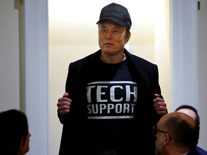 미국 정부효율부(DOGE) 수장인 일론 머스크 테슬라 최고경영자(CEO)가 26일(현지시간) 워싱턴 DC 백악관에서 도널드 트럼프 미국 대통령이 주최한 첫 내각 회의에서 연설하면서 ‘기술 지원’이라고 적힌 티셔츠를 보여주고 있다. [사진 = 로이터 연합뉴스]