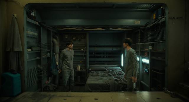 행성 당 1명만 허용된 익스펜더블이 둘이 된 ‘멀티플’ 상황에서 죽을 위기에서 돌아온 미키 17이 이미 프린트되어 있는 미키 18을 마주하고 있다. 사진제공=Warner Bros.