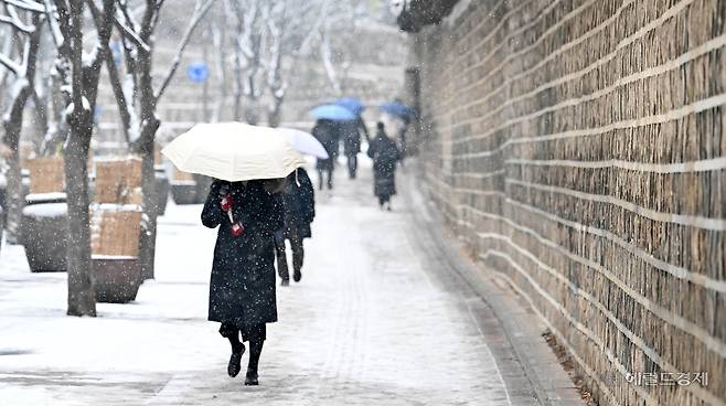 전국 곳곳에 눈이 내리던 지난 2월 12일 오전 서울 중구 덕수궁 돌담길에서 시민들이 우산으로 눈을 가리며 지나고 있다. 임세준 기자