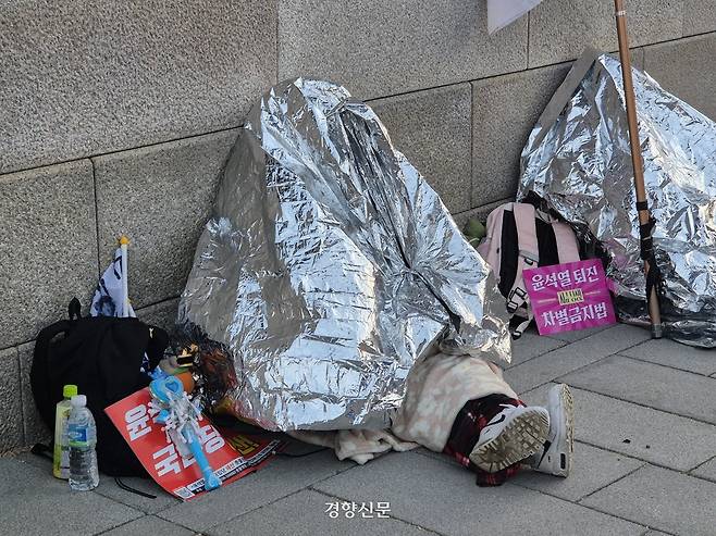 윤 대통령이 석방된 다음날이 9일 오전 6시20분쯤 서울 종로구 광화문 서십자각에서 철야 집회에 나선 시민들이 은박 담요를 두른 채 앉아 있다. 이예슬 기자
