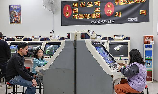 서울 동대문구 청량오락실에서 아버지와 두 딸이 즐겁게 스트리트 파이터 2 게임을 즐기고 있다.