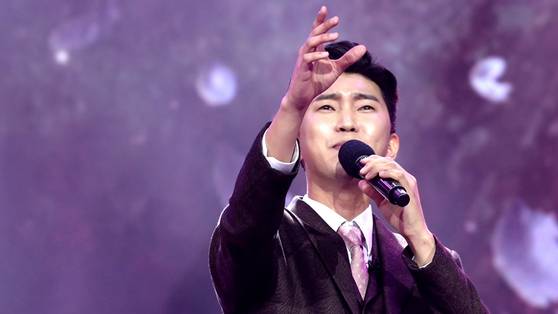 임영웅이 '미스터트롯'에서 '보라빛 엽서'를 부르고 있다. 손을 뻗는 제스처가 트로트 장르를 연상하게 한다. 사진 TV조선