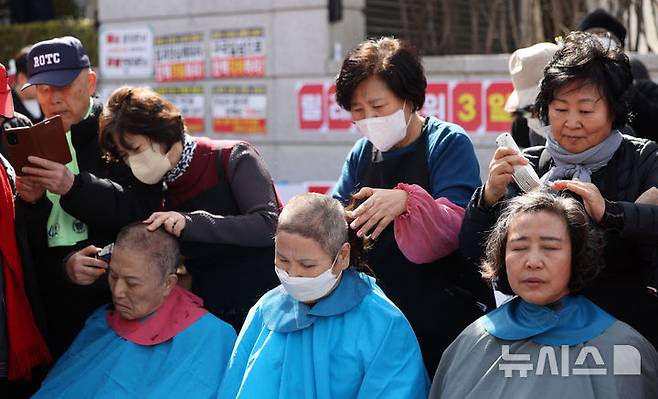 [서울=뉴시스] 김선웅 기자 = 헌재의 윤석열 대통령에 대한 탄핵심판 선고가 임박한 13일 서울 종로구 헌법재판소 앞에서 친 윤 성향 시민들이 탄핵을 반대하며 삭발을 하고 있다. 2025.03.13. mangusta@newsis.com