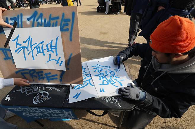 ‘윤석열즉각퇴진·사회대개혁 비상행동(비상행동)’이 15일 오후 서울 종로구 광화문 일대에서 연 ‘100만 시민 총집중의 날’ 집회에서 한 참가자가 ‘즉각파면’ 글자를 쓰고 있다. 김태형 기자