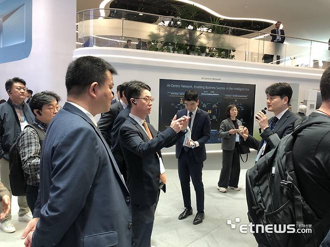 홍진배 IITP원장이 MWC25에서 기업 관계자 설명을 듣고 있다.