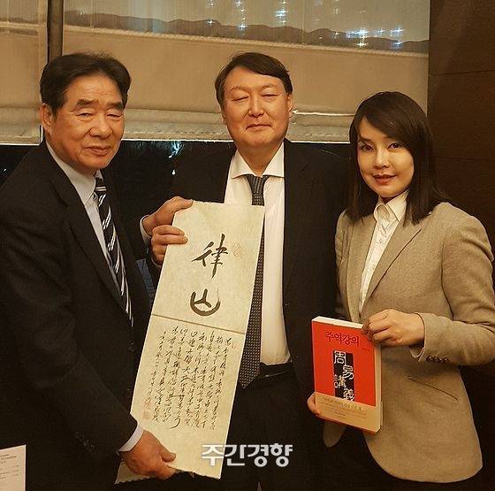 지난 2019년 2월 17일 역술인 서대원 씨(왼쪽)가 윤석열·김건희  부부를 만나 자신이 지어준 호 율산(律山)을 적은 글귀를 들고 기념사진을 찍고 있다.  /경향자료 사진, 서대원 제공