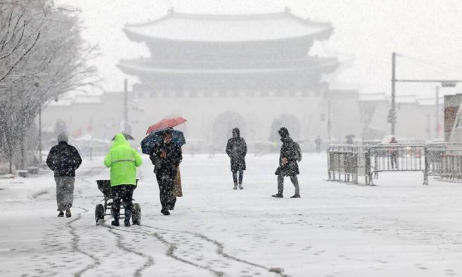 눈이 내린 18일 서울 종로구 광화문광장 위로 시민들이 출근길을 재촉하고 있다. 연합뉴스