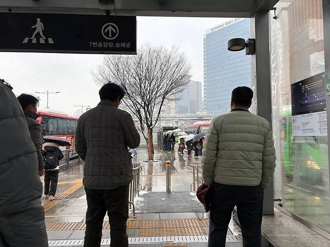 18일 아침 서울역 버스환승센터에서 시민들이 내리는 눈을 피하고 있다. 임재희 기자