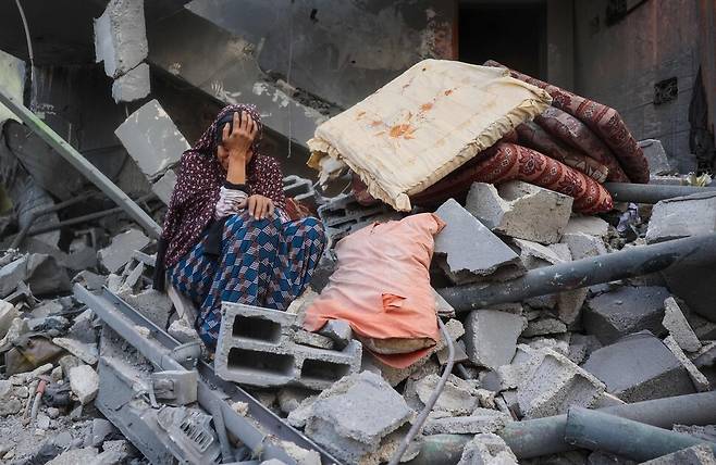 18일 팔레스타인 가자지구 중부 누세이라트 난민 캠프에서 여성 한 명이 이스라엘군 공습으로 무너진 집 앞에 주저앉아 울고 있다. AFP/연합뉴스