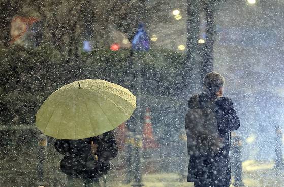 18일 새벽 서울 종로구 도심을 지나는 시민들이 거센 눈발을 피해 발걸음을 재촉하고 있다. 뉴스1