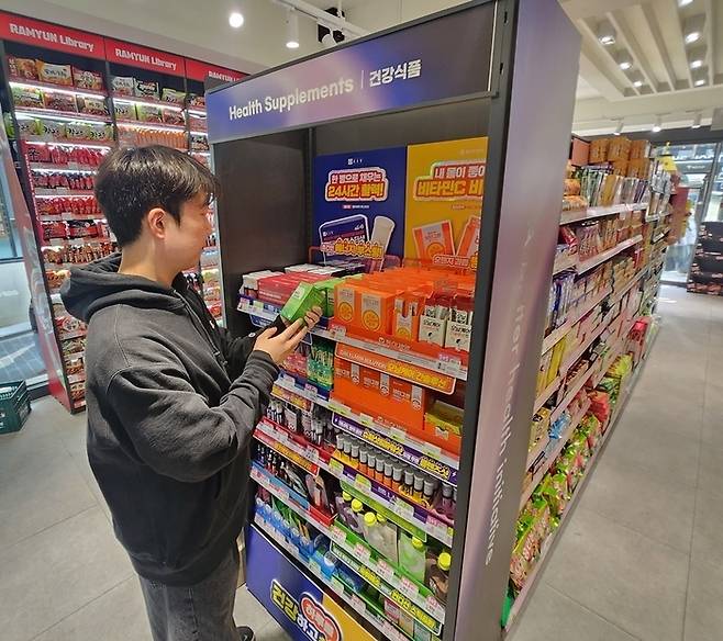 모델이 CU 건강식품 진열 강화점(명동점)에서 상품을 살펴보고 있다.