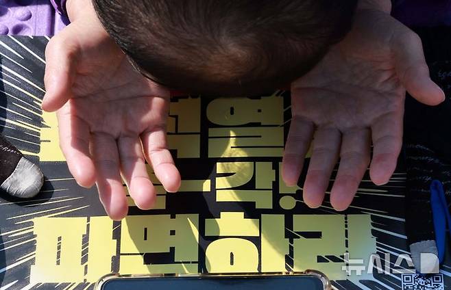 [서울=뉴시스] 고범준 기자 = 10.29 이태원 참사 유가족협의회, 시민대책회의 관계자들이 19일 서울 종로구 광화문 월대 옆에서 윤석열 대통령 파면 기원 159배를 하고 있다. 2025.03.19. bjko@newsis.com