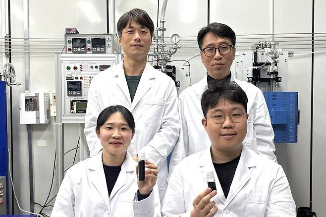 한국탄소산업진흥원 김동영 (왼쪽 뒷줄)박사 연구팀이 이산화탄소를 단일벽 탄소나노튜브로 전환하는 설비 앞에서 연구 성과물을 들어 보이고 있다.한국탄소산업진흥원 제공